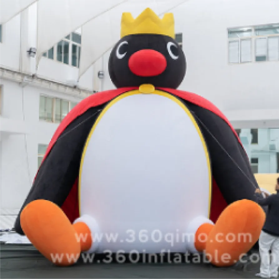Front view of 5m high crown penguin plush inflatable wearing a golden crown and red cape