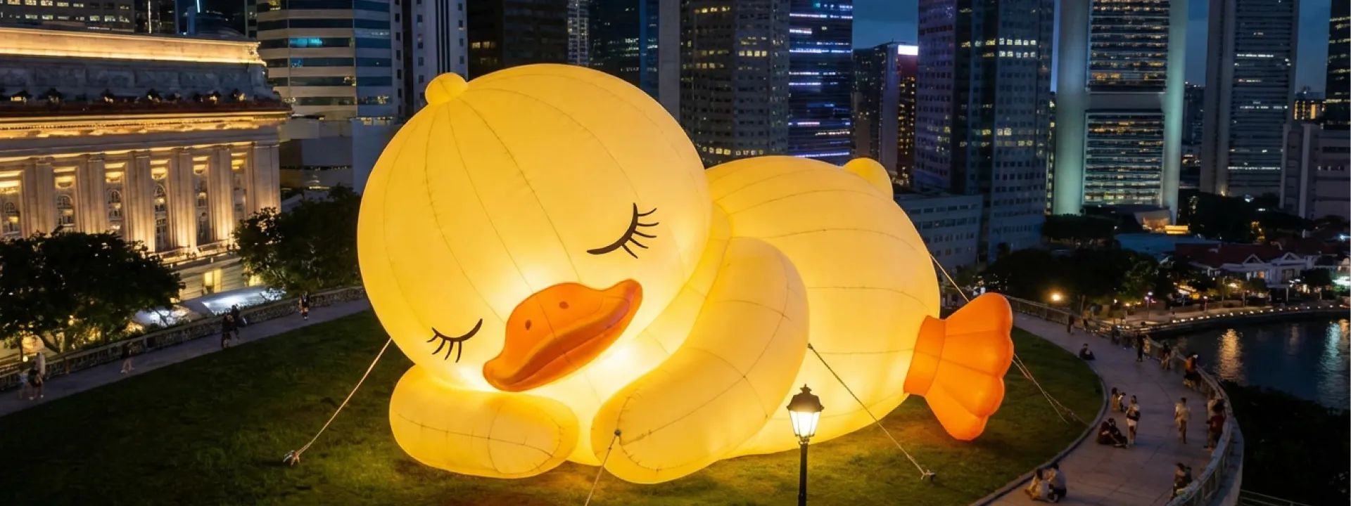 Large glowing inflatable yellow duck installation at night in city park